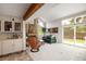 Bright living room featuring a fireplace, beamed ceiling, bar, and a seamless flow to the outdoor space at 10572 E Orchard Pl, Englewood, CO 80111
