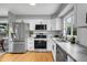 Bright kitchen featuring stainless steel appliances, white cabinets, and stone countertops at 2735 S Dahlia St, Denver, CO 80222