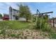 Backyard featuring a mature tree, gray siding, partially obscured swing set, and a sloping lawn at 19140 E Milan Cir, Aurora, CO 80013