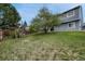 Spacious backyard featuring a mature shade tree, gray home exterior, and a swing set at 19140 E Milan Cir, Aurora, CO 80013