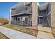 Condo with gray siding, stone accents, covered balcony, and second story access at 3482 S Eagle St # 102, Aurora, CO 80014