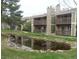 Exterior of a well-maintained apartment complex featuring a tranquil pond reflecting the building's architecture at 3482 S Eagle St # 102, Aurora, CO 80014