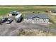 Aerial view of a gray single-story home, RV, detached garage, and parked trucks at 11809 Pass Me By Rd, Strasburg, CO 80136