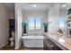 Bright bathroom featuring a standalone tub beneath a window, complemented by a modern vanity and fixtures at 11809 Pass Me By Rd, Strasburg, CO 80136