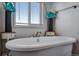 Close up of standalone bathtub with decorative flower vases near a window with blinds at 11809 Pass Me By Rd, Strasburg, CO 80136