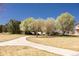 Sidewalk path leads through the park with mature trees, green grass, and blue sky at 15594 E 97Th Ave, Commerce City, CO 80022