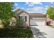 Charming brick home boasts a well-maintained lawn, mature trees, and a two-car garage at 15594 E 97Th Ave, Commerce City, CO 80022