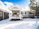 Rear exterior of home with covered porch and snowy yard at 8387 Fig St, Arvada, CO 80005