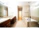 Well-lit bathroom features double sinks, soaking tub with shower, and neutral tile at 8387 Fig St, Arvada, CO 80005
