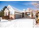 Charming two-story home featuring brick accents, a welcoming front porch, gray siding, and a gray two car garage at 8387 Fig St, Arvada, CO 80005