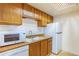 Galley kitchen featuring wooden cabinets and white appliances at 904 S Walden Way # 203, Aurora, CO 80017