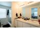 Bright bathroom featuring double sinks, a large mirror with vanity lighting, and a glass-enclosed shower at 26985 E Bayaud Ave, Aurora, CO 80018