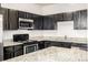Close up of modern kitchen featuring stainless steel appliances, granite countertops, and dark wood cabinets at 4100 Albion St # 523, Denver, CO 80216