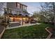 Spacious backyard with a deck, hot tub, string lights, and manicured lawn at 1271 Berganot Trl, Castle Pines, CO 80108
