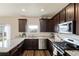 This kitchen features dark cabinets, granite countertops, stainless steel appliances, and wood-look flooring at 7232 Shavano Ave, Frederick, CO 80504