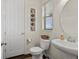Cozy powder room with pedestal sink, decorative wall art, and dark wood flooring at 8464 E 55Th Pl, Denver, CO 80238