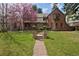 Charming two-story brick home with lush green lawn and vibrant flowering tree at 239 Ash St, Denver, CO 80220