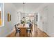 Open dining area with a long wooden table, modern light fixture, and view into the kitchen at 1833 E Jewell Ave, Denver, CO 80210