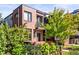 Modern brick house with a balcony, a well-manicured yard, and mature trees, offering privacy and curb appeal at 1833 E Jewell Ave, Denver, CO 80210