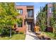 Modern brick home features a small balcony and lush landscaping around the front yard and walkway in a vibrant neighborhood at 1833 E Jewell Ave, Denver, CO 80210