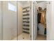 Modern tiled shower with glass door adjacent to a walk-in closet with hanging storage at 1833 E Jewell Ave, Denver, CO 80210