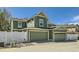 Green two-story home features two garage doors, white picket fence and manicured landscaping at 17244 E Kansas Dr, Aurora, CO 80017