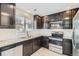 Well-equipped kitchen features granite countertops, stainless steel appliances, and sleek dark cabinetry for modern cooking at 17244 E Kansas Dr, Aurora, CO 80017