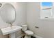 A well-lit half bathroom with an oval mirror above a pedestal sink and a modern toilet at 5698 Farrier Pt, Castle Rock, CO 80104