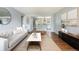 Sunlit living room featuring a modern sofa, wood floors and an open layout leading into a kitchen area at 8240 Grandview Ave, Arvada, CO 80002