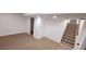 Finished basement area with neutral carpet, stairs, and door to storage, creating a versatile living space at 6521 Zinnia St, Arvada, CO 80004