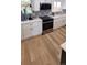 Modern kitchen featuring stainless steel appliances, white cabinetry, and bright wooden floors at 6521 Zinnia St, Arvada, CO 80004