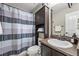 Bathroom with a single sink vanity, dark wood cabinet, toilet, and shower with curtains at 19603 E 63Rd Pl, Aurora, CO 80019