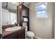 Bathroom featuring a vanity, dark wood cabinets, open shelving, and a window at 19603 E 63Rd Pl, Aurora, CO 80019