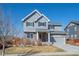 Inviting two-story home with stone accents, gray siding, and a well-maintained lawn on a clear, sunny day at 19603 E 63Rd Pl, Aurora, CO 80019