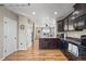 Well-designed kitchen with dark cabinetry, stainless appliances, hardwood floors, and open access to the living room at 19603 E 63Rd Pl, Aurora, CO 80019