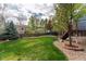 Expansive backyard with lush green lawn, mature trees, wood fence, and landscaped areas at 2822 Flint Ct, Superior, CO 80027