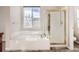 Bathroom featuring a tiled tub, a glass-enclosed shower, and a large window for natural light at 461 Saber Creek Dr, Monument, CO 80132