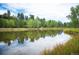 Reflective pond surrounded by lush greenery, with the sky's reflection, enhancing the serene atmosphere of the area at 23566 Pondview Pl # F, Golden, CO 80401
