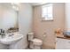 Stylish powder room featuring a pedestal sink, modern toilet, and decorative accents under natural light at 8361 Parkland St, Broomfield, CO 80021