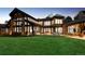 Stunning home exterior with stone accents, large windows, and expansive lawn with patio seating at dusk at 4475 S Downing St, Cherry Hills Village, CO 80113