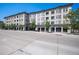 A street-level view of a multi-story building with commercial spaces, trees, and a wide city street at 277 N Broadway # 403, Denver, CO 80203