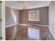 Empty bedroom with light brown walls, wood floor, a chandelier, and natural light from a window at 22388 Quail Run Dr, Parker, CO 80138