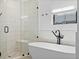 Close up of the bright bathroom featuring a glass-enclosed shower and freestanding tub with black matte fixtures at 4454 Utica St, Denver, CO 80212