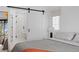 Bright bedroom featuring a modern sliding barn door, sleek minimalist design, and an en suite bathroom at 4454 Utica St, Denver, CO 80212