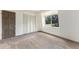 An empty bedroom with neutral-toned carpet, a large window, and a closet with bi-fold doors at 9349 E Chenango Ave, Greenwood Village, CO 80111