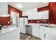 A kitchen featuring white cabinets, stainless steel appliances, wood-style floors, and a vibrant red wall at 9349 E Chenango Ave, Greenwood Village, CO 80111