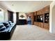Cozy living room with a fireplace, built-in shelving, and dark leather sofa and piano with carpeted floor at 13970 Craig Way, Broomfield, CO 80020
