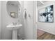 Stylish powder room featuring a pedestal sink, a round mirror, and modern fixtures, offering a touch of elegance at 4060 N Rome St, Aurora, CO 80019