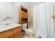 Bathroom with vanity, toilet, storage cabinet, and shower with white shower curtain at 9816 Garwood St, Littleton, CO 80125