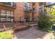 A tranquil courtyard features a stone patio, bench seating, and brick building with black accents in the background at 930 Acoma St # 108, Denver, CO 80204